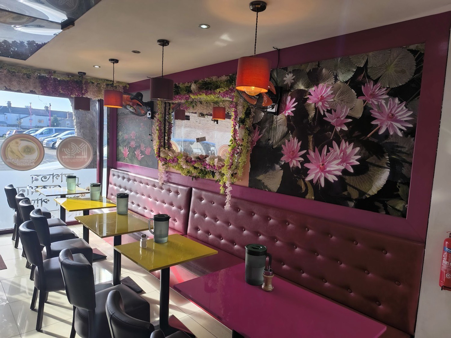Inside Moon Coffee & Restaurant — red leather booths, yellow tables and a water-lily mural on the wall